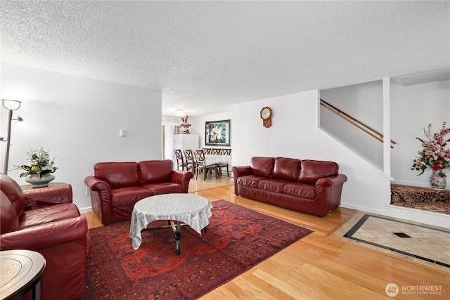 living room featuring stairway, wood finished floors, and a textured ceiling