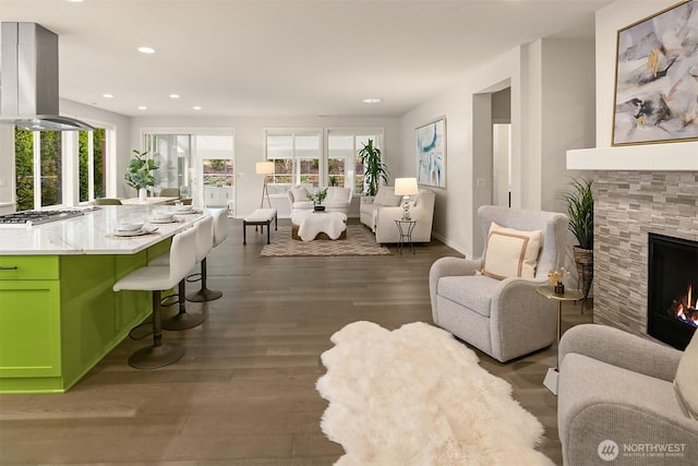 living room with a tile fireplace, a healthy amount of sunlight, and wood finished floors