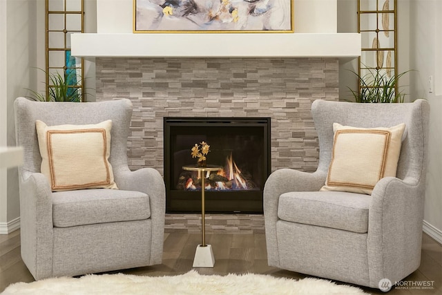 living area featuring baseboards, a tiled fireplace, and wood finished floors