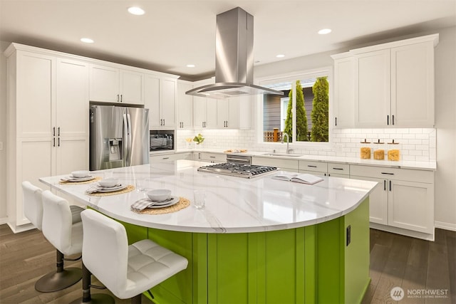 kitchen featuring appliances with stainless steel finishes, white cabinets, a sink, and island range hood