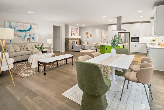 dining area featuring light wood-style floors, a fireplace, and recessed lighting