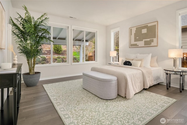 bedroom with baseboards, visible vents, and wood finished floors