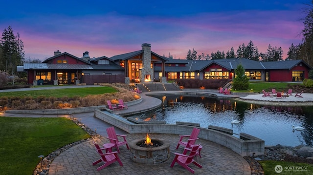 back of house at dusk featuring a patio area, a fire pit, and a yard