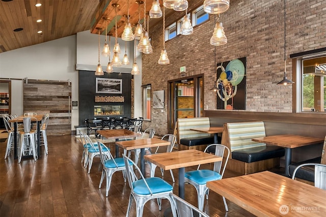 dining room featuring hardwood / wood-style flooring, wood ceiling, brick wall, high vaulted ceiling, and a multi sided fireplace