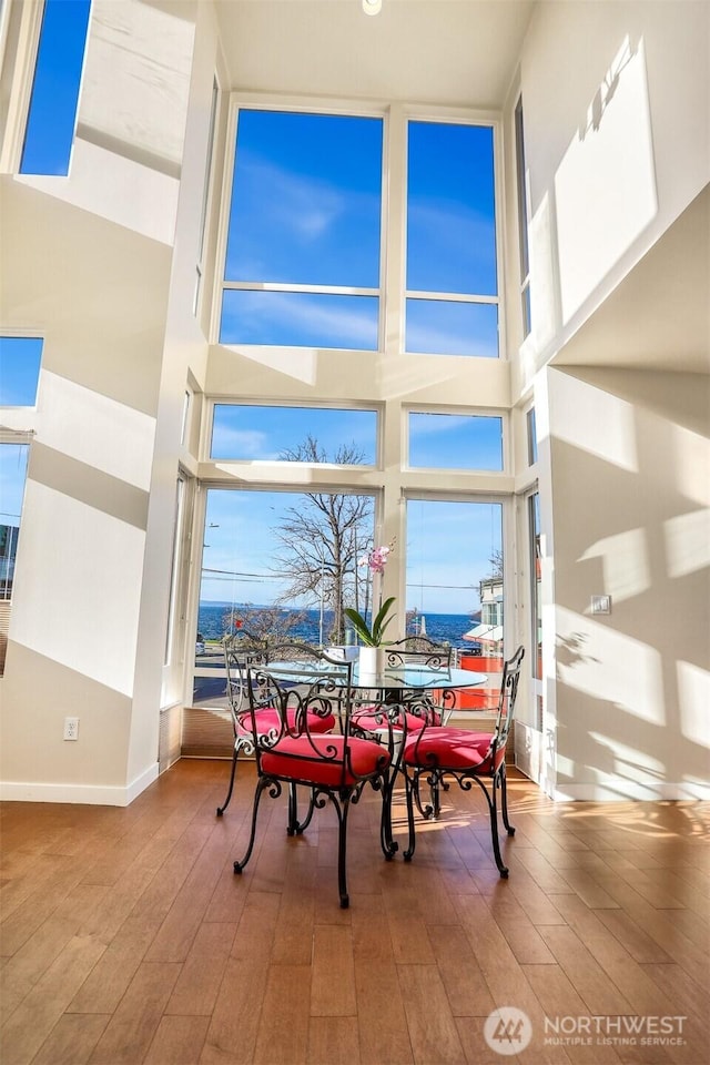 dining area featuring a towering ceiling, baseboards, and wood finished floors