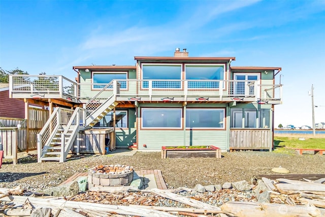 rear view of property with stairway, fence, an outdoor fire pit, a chimney, and a deck