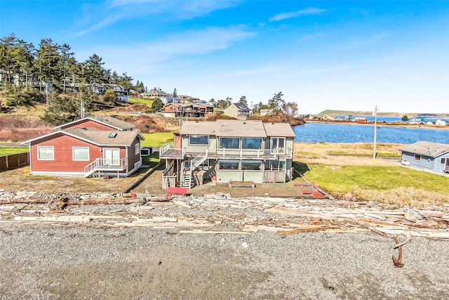 view of front of home with a residential view, a sunroom, and a water view