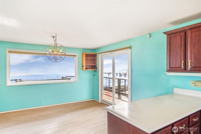 kitchen featuring an inviting chandelier, light wood-style flooring, hanging light fixtures, and light countertops