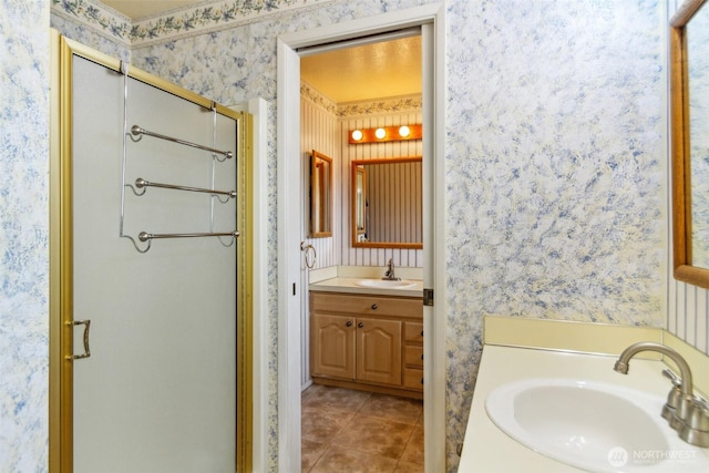 full bath featuring vanity, a stall shower, tile patterned flooring, and wallpapered walls