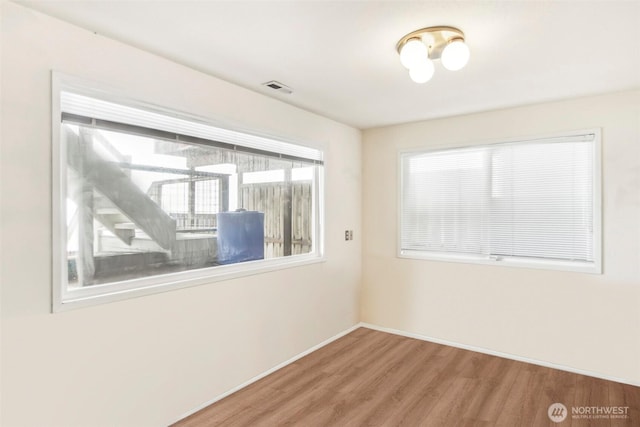 spare room with visible vents, baseboards, and wood finished floors