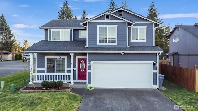 traditional-style home featuring driveway, a garage, a porch, fence, and a front lawn