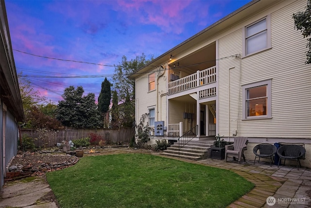 back of house featuring a yard, fence, and a balcony