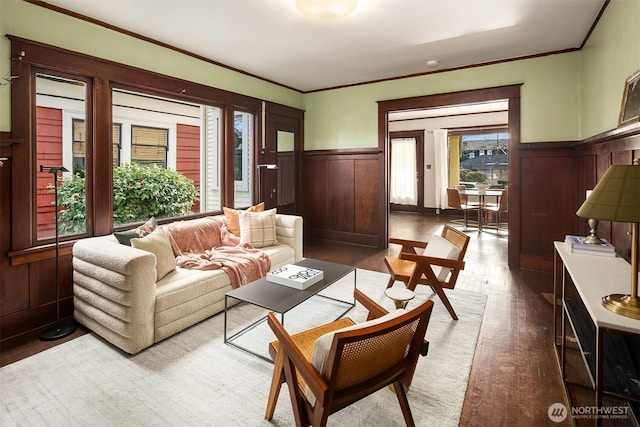 living room with a wainscoted wall, ornamental molding, and wood finished floors