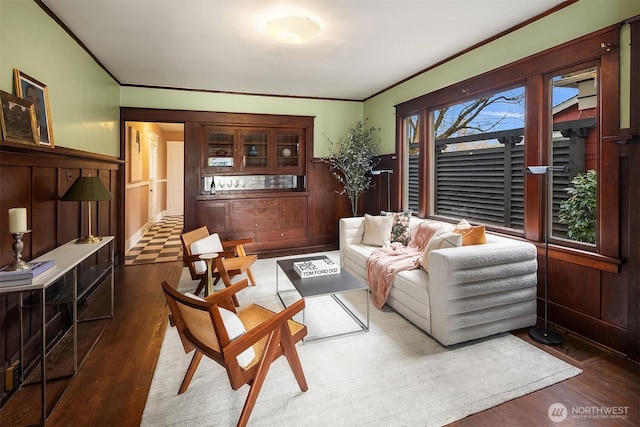 living room with a wainscoted wall, crown molding, and wood finished floors