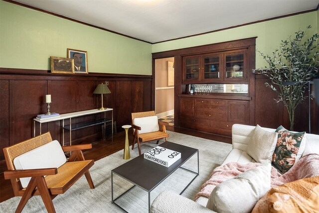 living room featuring wood finished floors, crown molding, and wainscoting