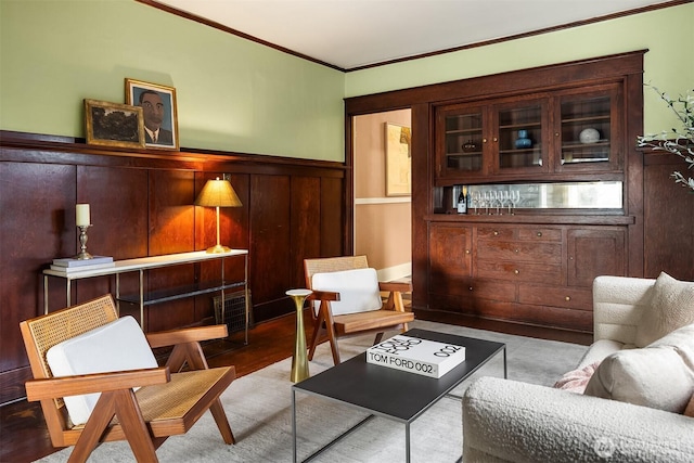 sitting room featuring ornamental molding, wainscoting, and wood finished floors