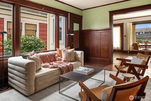 interior space with a wainscoted wall, ornamental molding, and wood finished floors