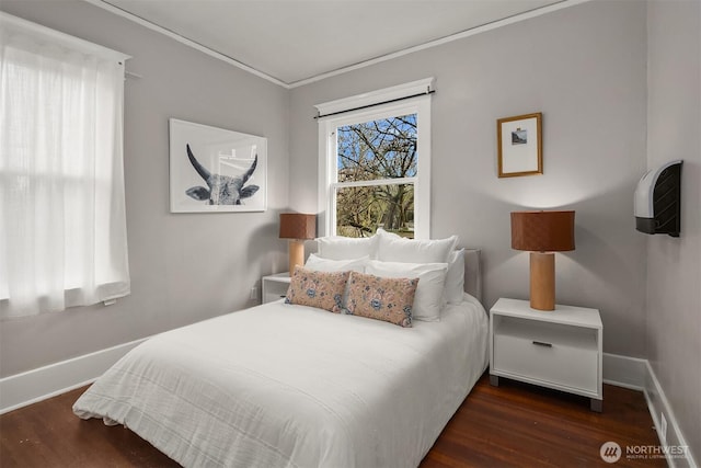 bedroom with ornamental molding, baseboards, and wood finished floors