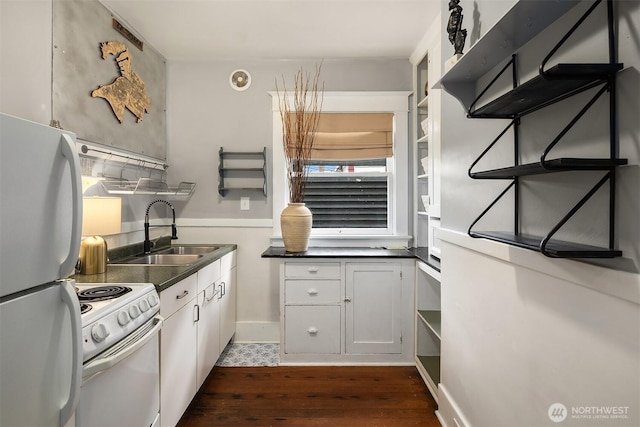 kitchen featuring dark countertops, white appliances, dark wood finished floors, and a sink