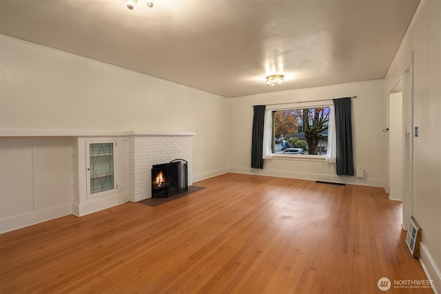 unfurnished living room featuring light wood-style flooring, a fireplace, and visible vents