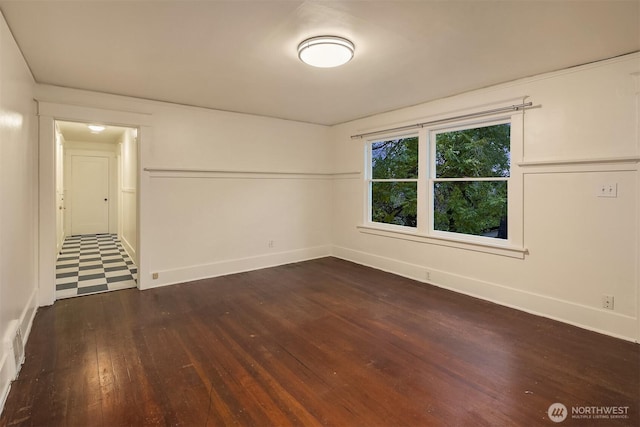 spare room featuring dark wood-style flooring and baseboards