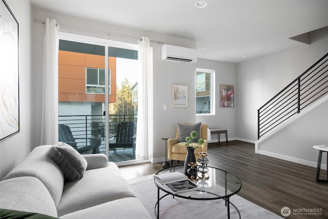 living area with a wall mounted air conditioner, stairway, baseboards, and wood finished floors