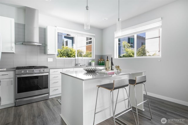 kitchen with a kitchen island, a sink, stainless steel gas range, backsplash, and wall chimney exhaust hood