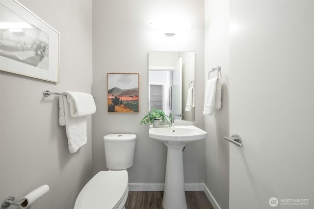 half bathroom with a sink, wood finished floors, toilet, and baseboards