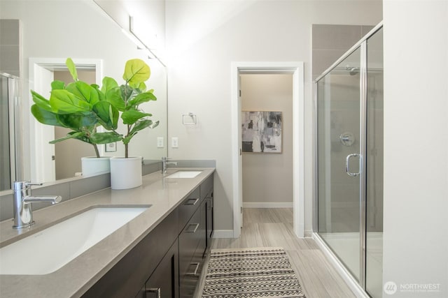 bathroom with double vanity, a stall shower, and a sink