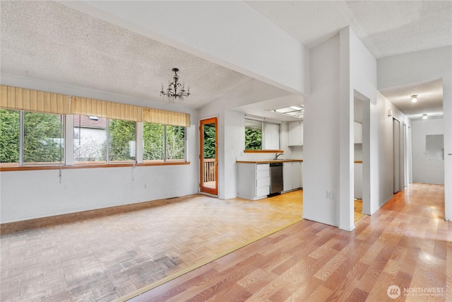 spare room featuring parquet floors, a notable chandelier, baseboards, and a textured ceiling