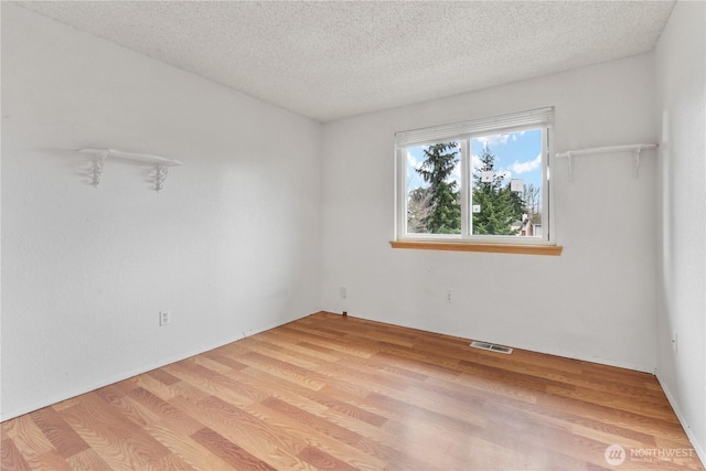 spare room featuring visible vents, a textured ceiling, and light wood-style floors