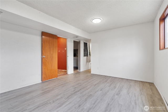 unfurnished room featuring baseboards, a textured ceiling, and wood finished floors