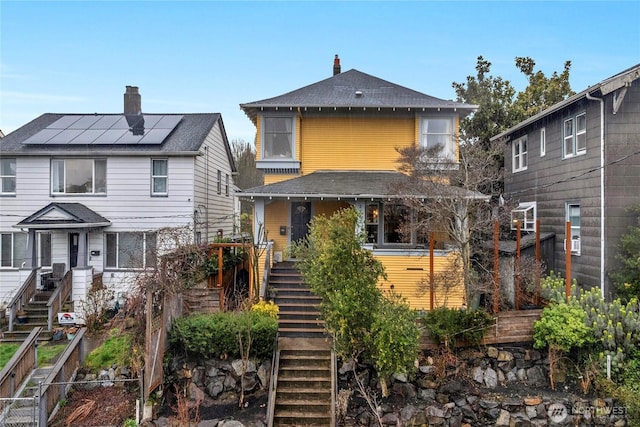 view of front of property featuring stairway, solar panels, and fence