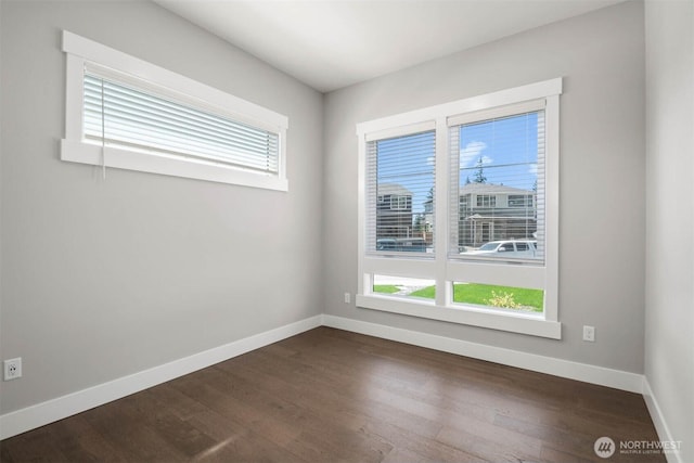 unfurnished room with dark wood-type flooring and baseboards