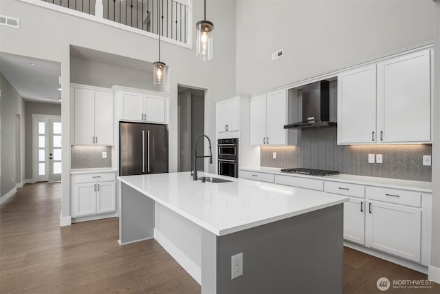 kitchen featuring wall chimney exhaust hood, stainless steel appliances, tasteful backsplash, visible vents, and dark wood-style floors