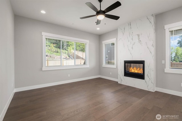 unfurnished living room with baseboards, recessed lighting, a ceiling fan, dark wood finished floors, and a premium fireplace