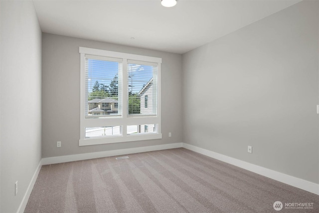 carpeted empty room featuring baseboards