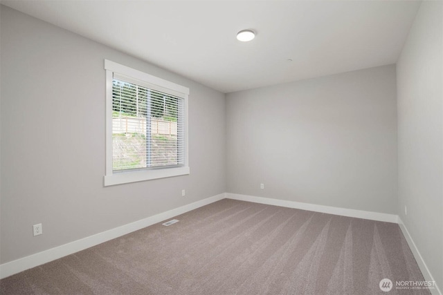 empty room featuring carpet floors, baseboards, and visible vents
