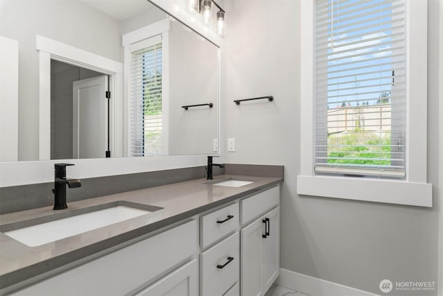 bathroom featuring baseboards, a sink, marble finish floor, and double vanity