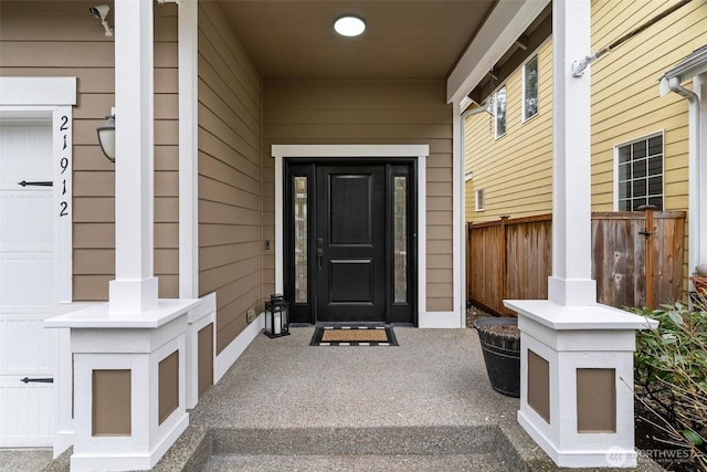 doorway to property featuring fence and a garage