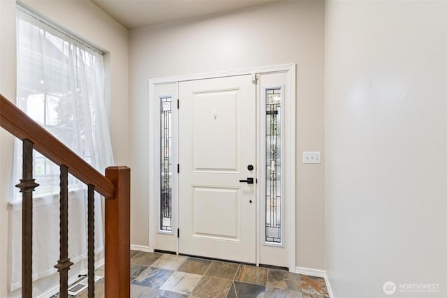 entryway with stairs, baseboards, and stone finish flooring