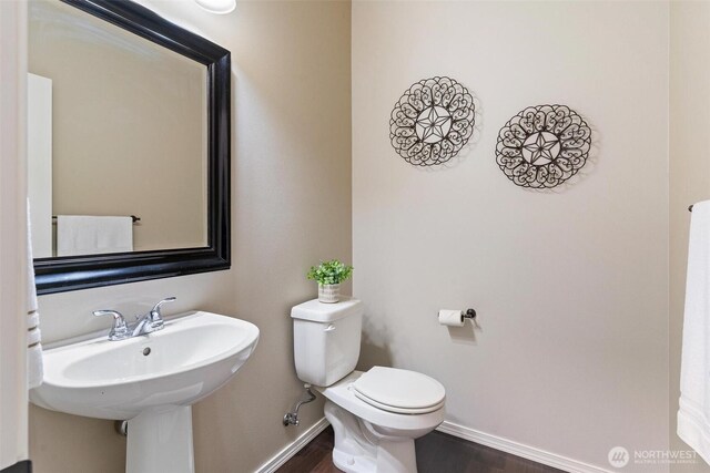 bathroom featuring toilet, wood finished floors, and baseboards