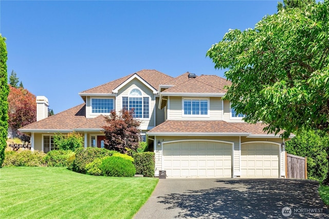 view of front of home featuring a front yard, roof with shingles, a chimney, a garage, and driveway