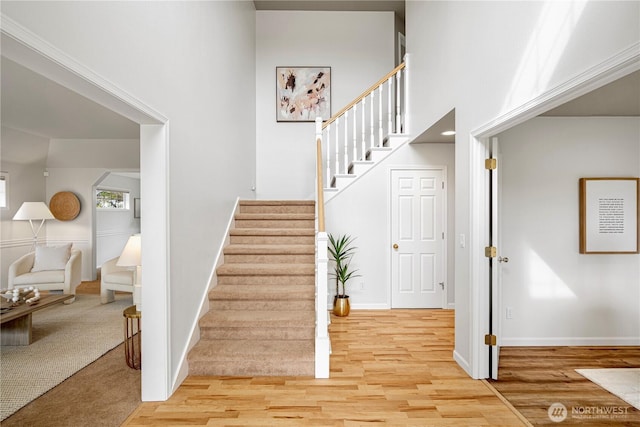 stairway with a high ceiling, wood finished floors, and baseboards