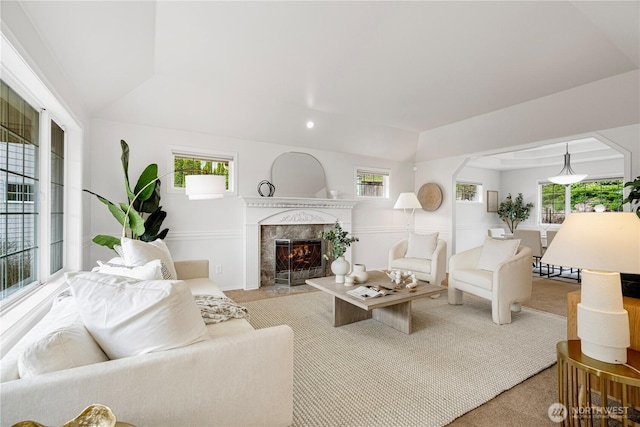 living room featuring a healthy amount of sunlight, a high end fireplace, and light carpet