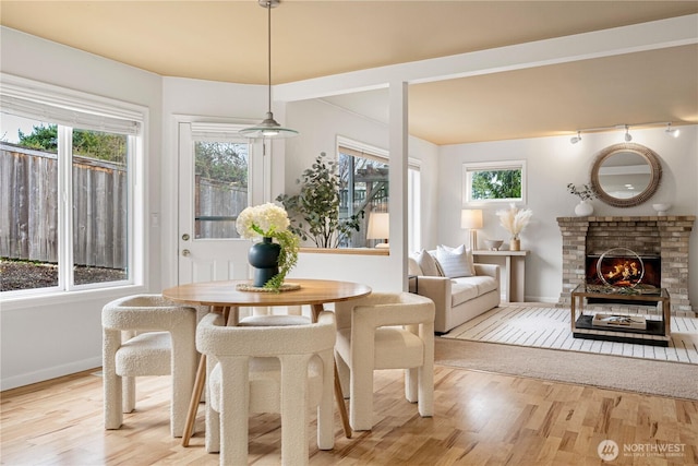 dining room with a brick fireplace, light wood-style floors, and baseboards