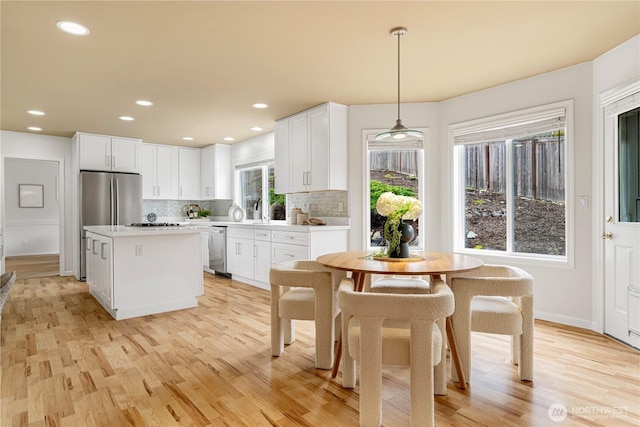 kitchen featuring tasteful backsplash, a kitchen island, white cabinetry, stainless steel appliances, and light countertops