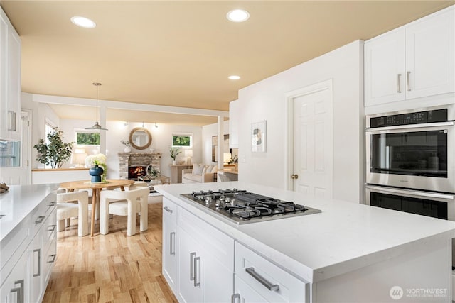 kitchen with white cabinets, recessed lighting, appliances with stainless steel finishes, and a lit fireplace