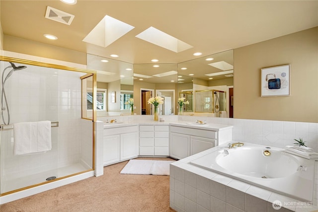 bathroom with vanity, visible vents, a skylight, a shower stall, and a bath