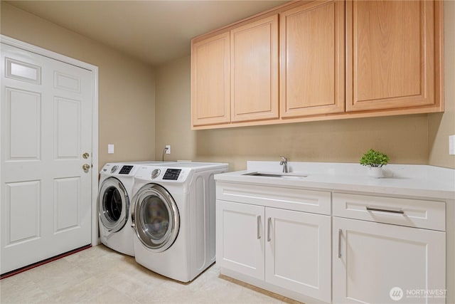 laundry room featuring washer and dryer, cabinet space, and a sink